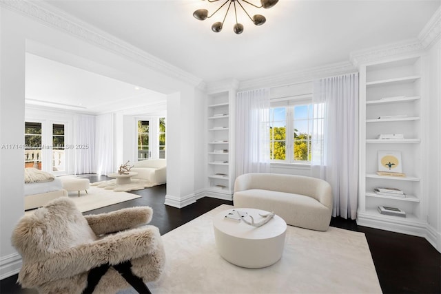 sitting room with a chandelier, built in shelves, dark wood-type flooring, and ornamental molding