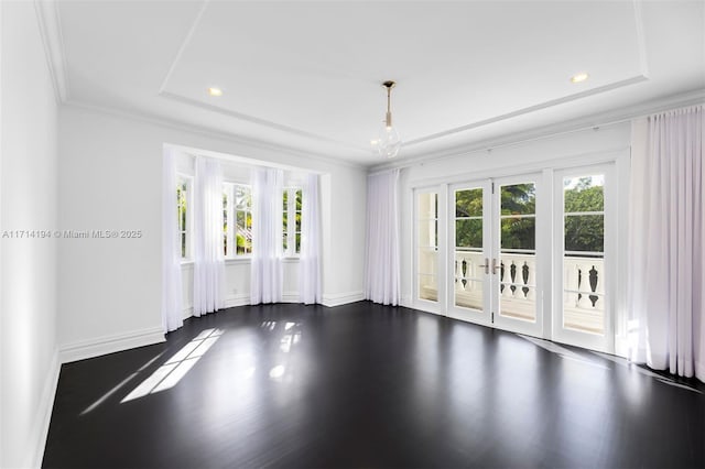 spare room featuring ornamental molding, a tray ceiling, and dark wood-type flooring