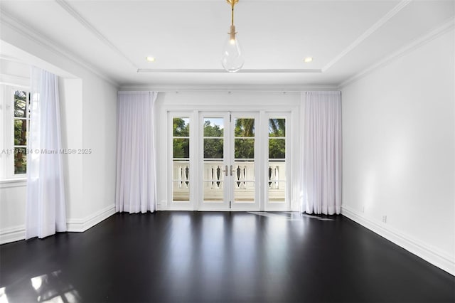 empty room with dark hardwood / wood-style floors, ornamental molding, a tray ceiling, and french doors