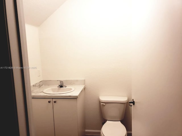 bathroom featuring vanity, toilet, and lofted ceiling