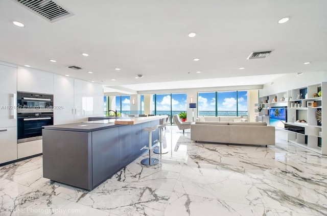 kitchen featuring a kitchen breakfast bar, a large island, stainless steel double oven, and white cabinetry