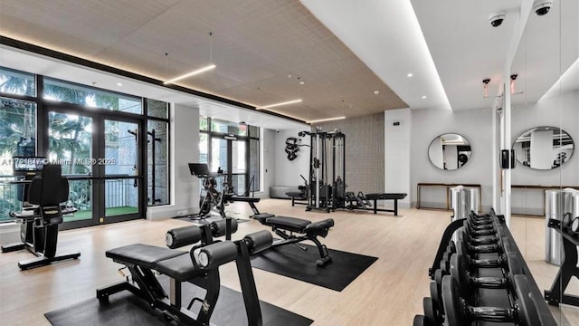 exercise room featuring expansive windows, light wood-type flooring, and french doors