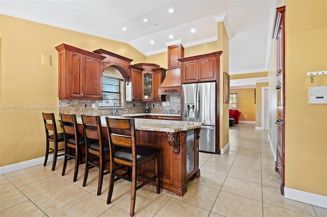 kitchen with stainless steel appliances, premium range hood, vaulted ceiling, a breakfast bar area, and decorative backsplash