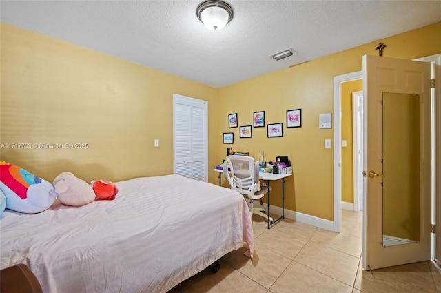 tiled bedroom featuring a textured ceiling and a closet