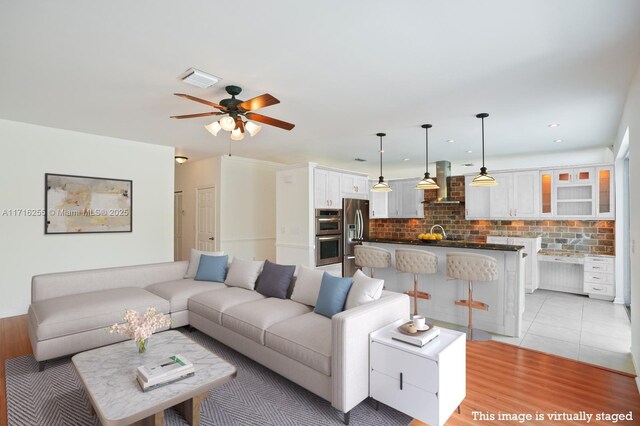 kitchen featuring pendant lighting, an island with sink, extractor fan, and stainless steel refrigerator with ice dispenser