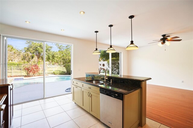 kitchen with appliances with stainless steel finishes, pendant lighting, sink, dark stone counters, and wall chimney range hood