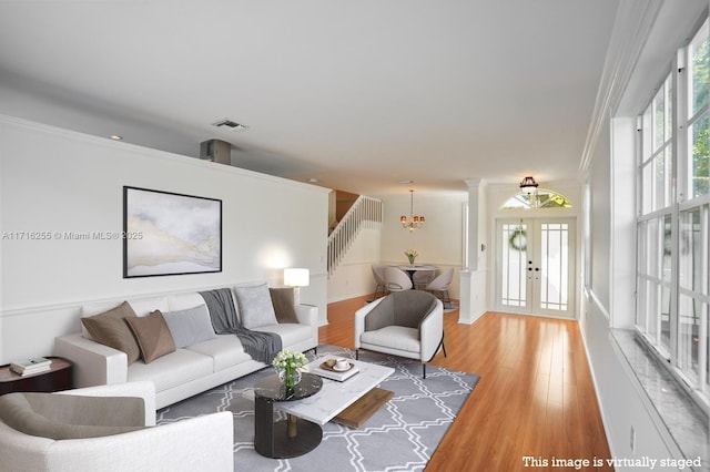 living room featuring a notable chandelier, hardwood / wood-style flooring, a wealth of natural light, and french doors