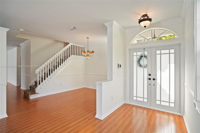 foyer entrance with an inviting chandelier, ornamental molding, french doors, and hardwood / wood-style flooring