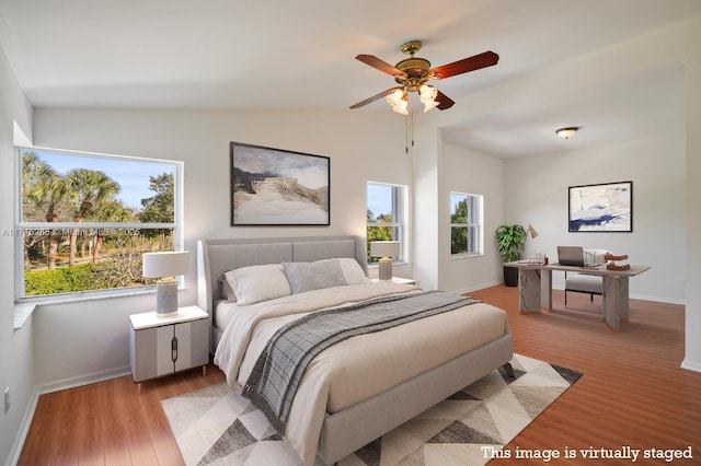 bedroom featuring multiple windows, lofted ceiling, ceiling fan, and light wood-type flooring