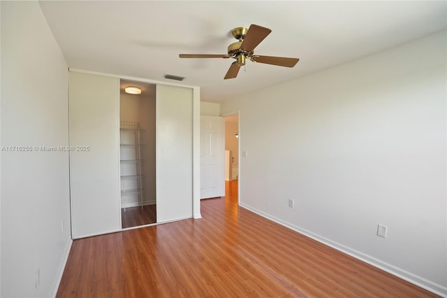 unfurnished bedroom featuring wood-type flooring, ceiling fan, and a closet