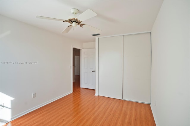 unfurnished bedroom with ceiling fan, wood-type flooring, and a closet