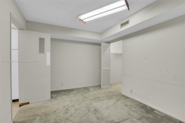 basement featuring a textured ceiling and light carpet