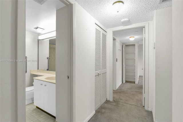 hall featuring light carpet and a textured ceiling