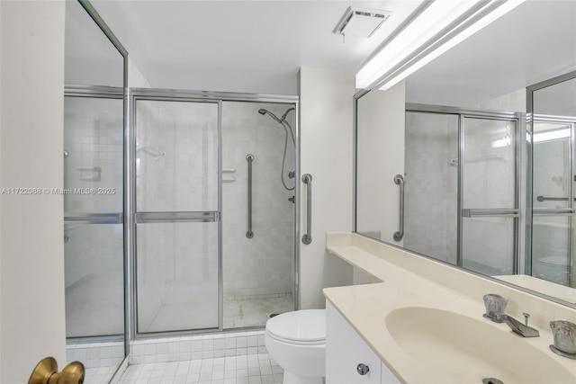 bathroom featuring vanity, toilet, and a shower with shower door