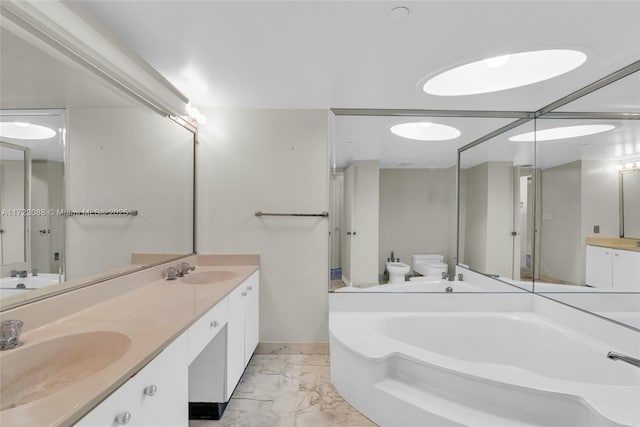 bathroom with vanity, toilet, a tub to relax in, and a bidet