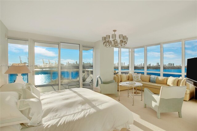 bedroom with a notable chandelier, a water view, and light colored carpet