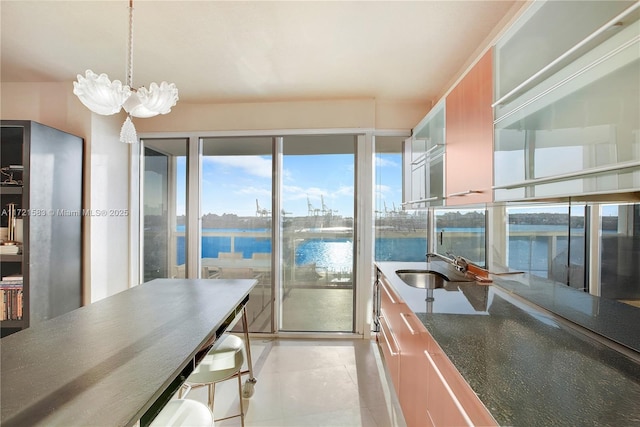 kitchen with pendant lighting, a water view, sink, and a chandelier