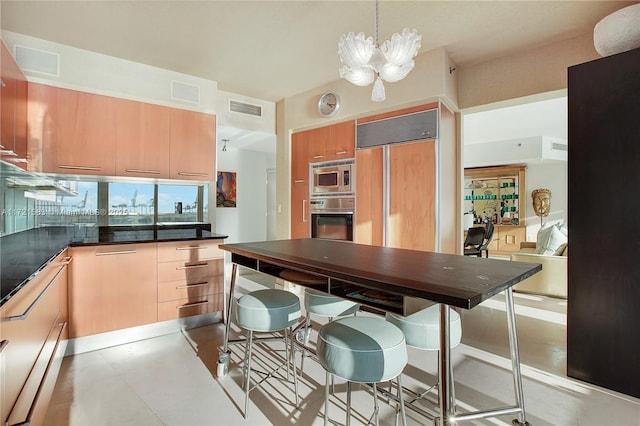 kitchen featuring built in appliances, a notable chandelier, hanging light fixtures, and light brown cabinetry