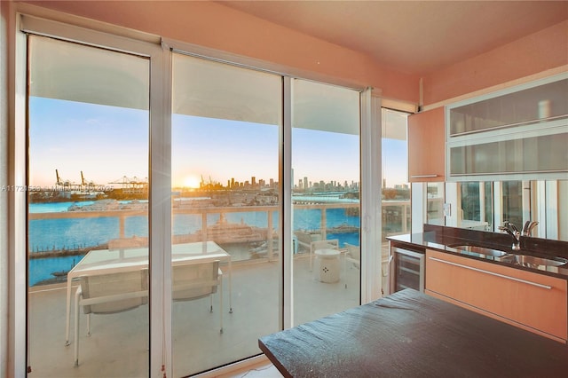 doorway to outside with a water view, sink, and wine cooler