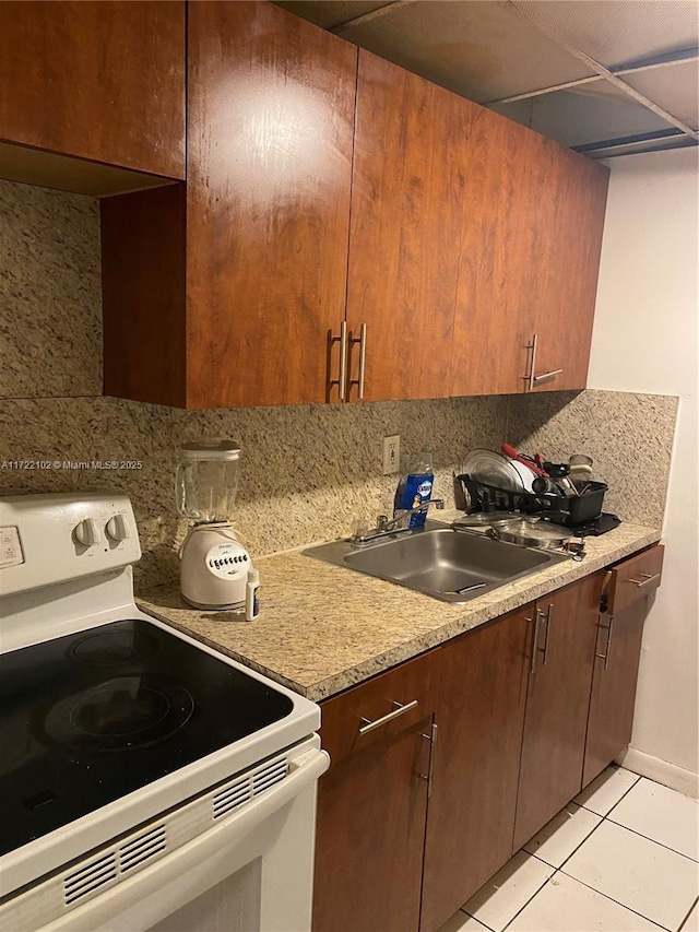 kitchen featuring decorative backsplash, sink, white range with electric stovetop, and light tile patterned flooring