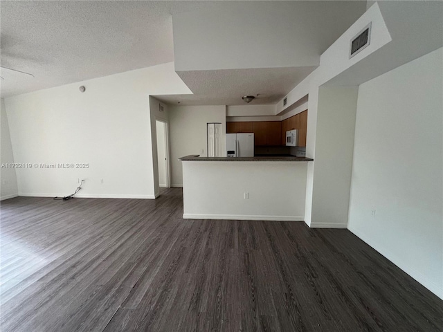 unfurnished living room featuring ceiling fan, dark wood-type flooring, and a textured ceiling