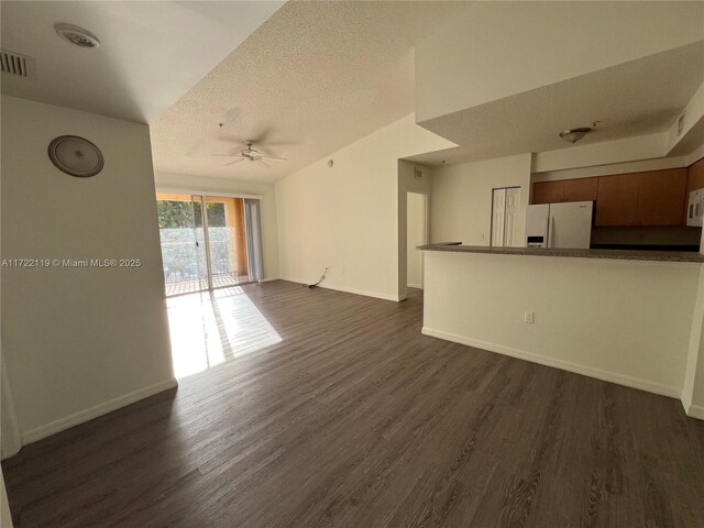 unfurnished living room featuring ceiling fan, dark wood-type flooring, and a textured ceiling