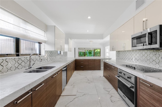 kitchen with sink, backsplash, dark brown cabinets, stainless steel appliances, and white cabinets