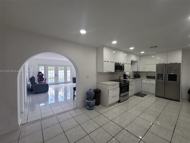 kitchen with french doors, stainless steel appliances, sink, light tile patterned floors, and white cabinets