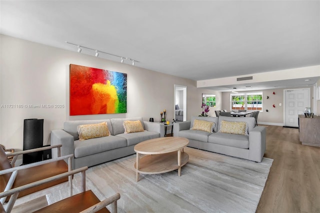 living room with light hardwood / wood-style floors and rail lighting