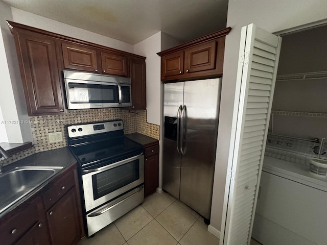 kitchen featuring sink, backsplash, washer / clothes dryer, light tile patterned floors, and appliances with stainless steel finishes