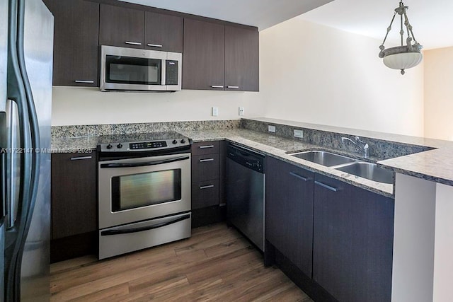 kitchen featuring dark brown cabinetry, sink, hanging light fixtures, dark hardwood / wood-style floors, and appliances with stainless steel finishes