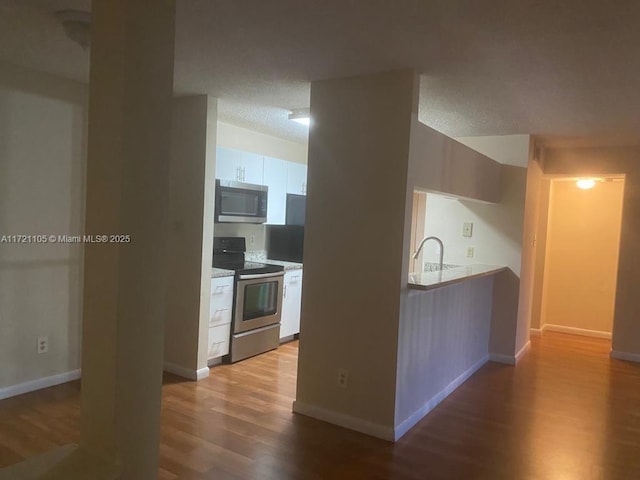 kitchen with white cabinetry, sink, wood-type flooring, and appliances with stainless steel finishes