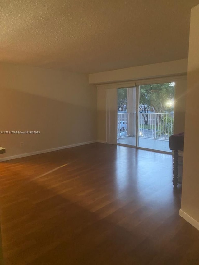 spare room with dark hardwood / wood-style flooring and a textured ceiling