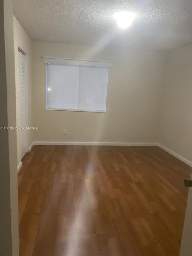 spare room with dark hardwood / wood-style flooring and a textured ceiling