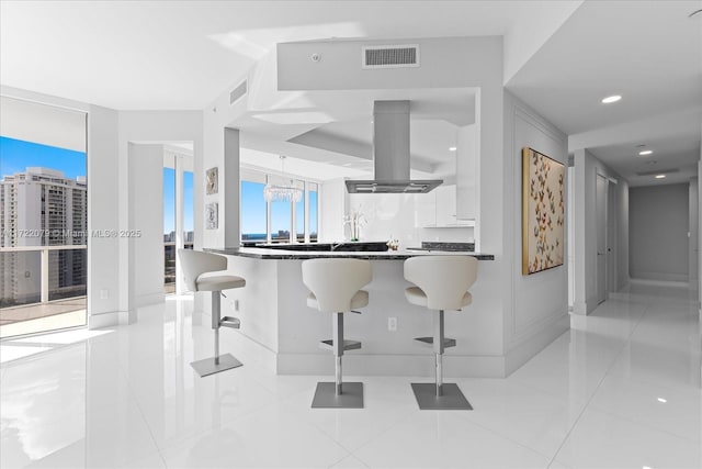 kitchen with white cabinetry, island range hood, a breakfast bar, and light tile patterned floors