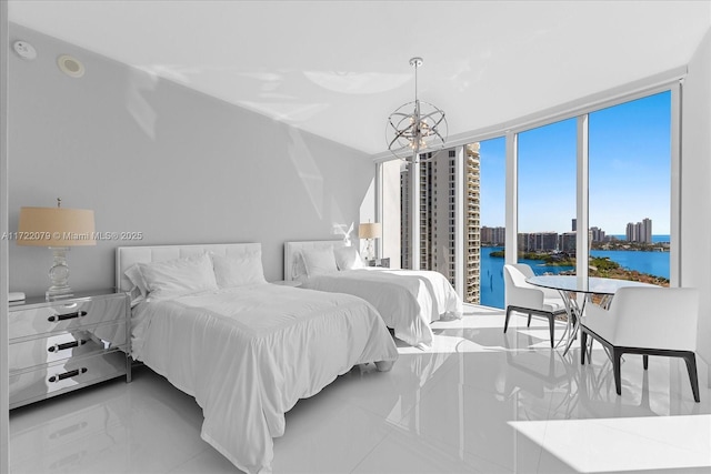 bedroom with a chandelier, a water view, and a wall of windows