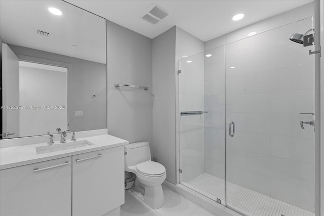 bathroom featuring tile patterned floors, vanity, a shower with shower door, and toilet