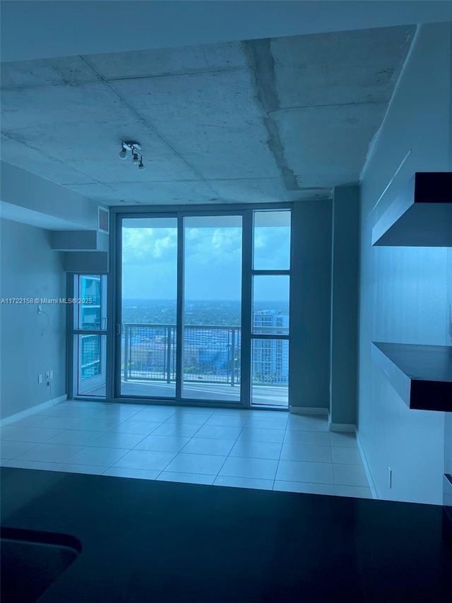 unfurnished room with a water view, light tile patterned floors, and a wall of windows