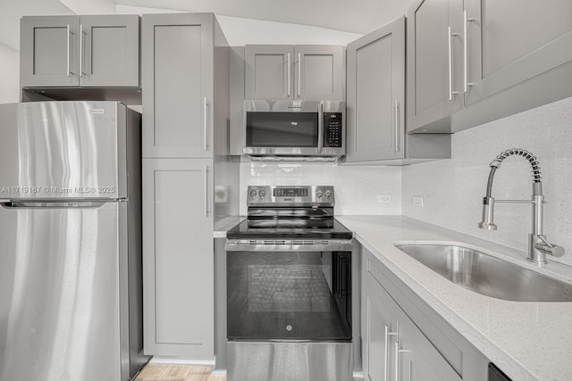 kitchen featuring tasteful backsplash, gray cabinets, sink, and appliances with stainless steel finishes