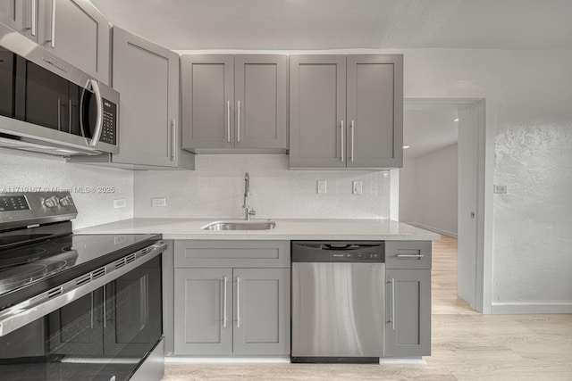 kitchen featuring gray cabinets, sink, light hardwood / wood-style floors, and stainless steel appliances