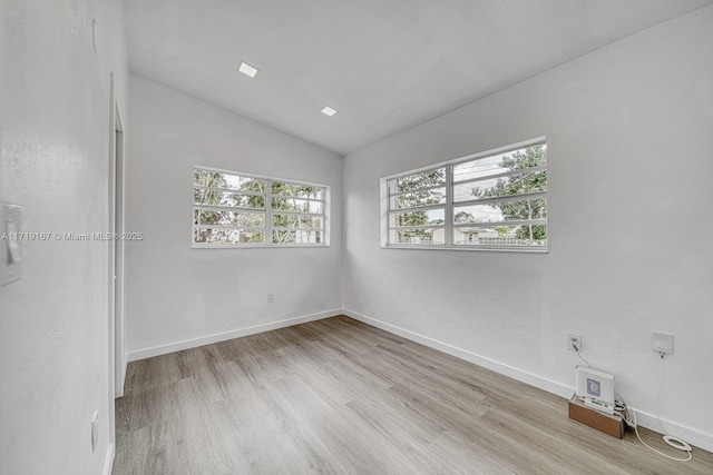 unfurnished room with lofted ceiling and light hardwood / wood-style flooring