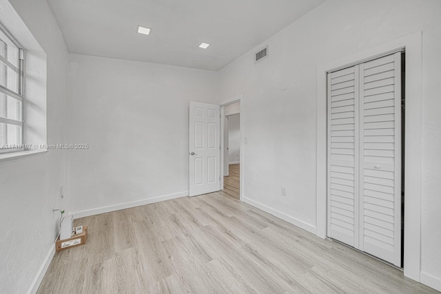 unfurnished bedroom featuring light hardwood / wood-style flooring and a closet