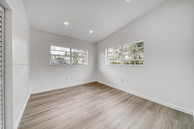 unfurnished room with light hardwood / wood-style floors and vaulted ceiling