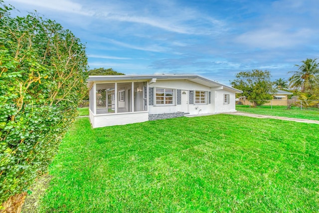 back of property featuring a sunroom and a lawn