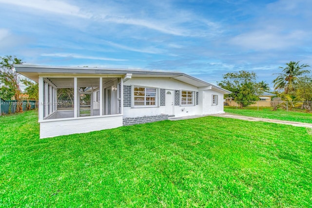 back of house featuring a sunroom and a lawn