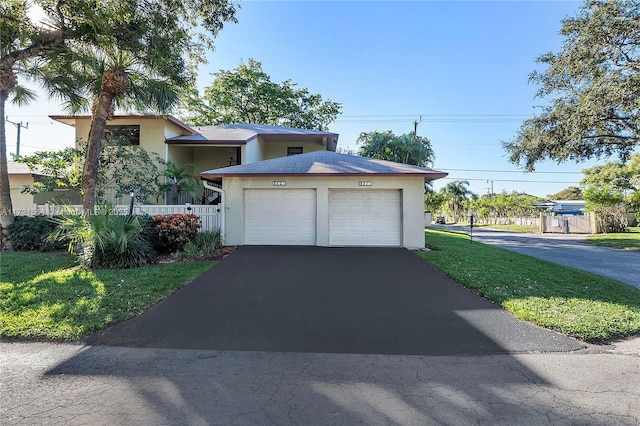 view of front of house featuring aphalt driveway, fence, a garage, and stucco siding