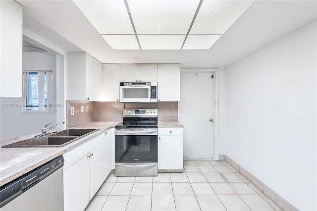 kitchen featuring light countertops, decorative backsplash, stainless steel appliances, white cabinetry, and a sink