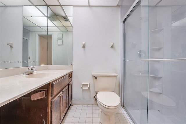 bathroom with tile patterned flooring, a drop ceiling, a stall shower, and toilet