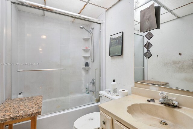 bathroom with a paneled ceiling, a shower with door, vanity, tile patterned floors, and toilet