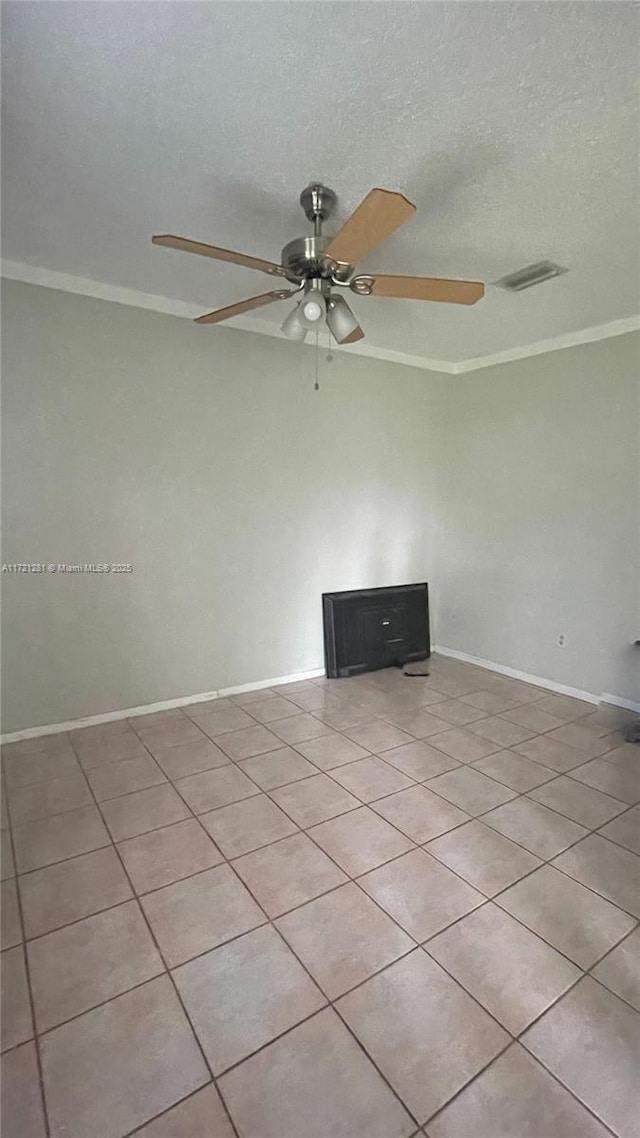 empty room with ceiling fan, ornamental molding, light tile patterned floors, and a textured ceiling